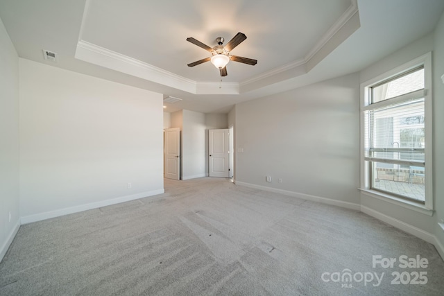 spare room with a raised ceiling, crown molding, visible vents, and baseboards