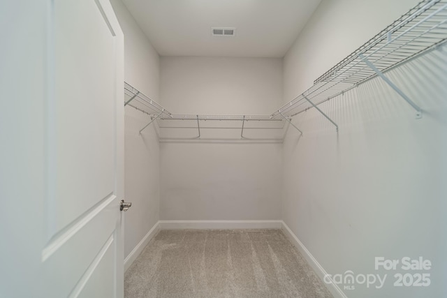 walk in closet with visible vents and light colored carpet