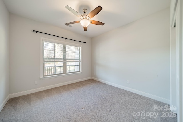 carpeted spare room featuring ceiling fan and baseboards