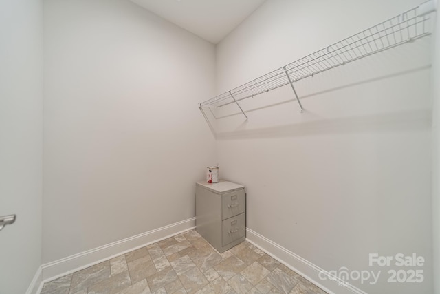 walk in closet featuring stone finish floor