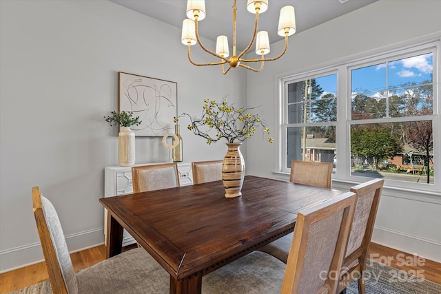 dining room with baseboards, a notable chandelier, and wood finished floors