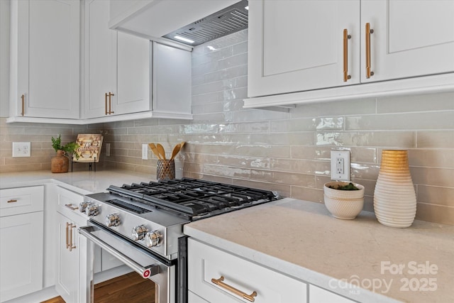 kitchen with light stone countertops, stainless steel gas range, decorative backsplash, custom range hood, and white cabinets