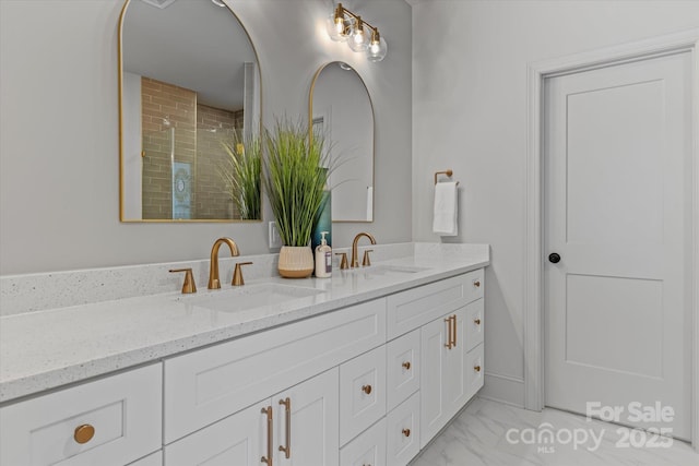 full bathroom featuring a sink, tiled shower, marble finish floor, and double vanity