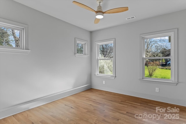 unfurnished room with wood finished floors, baseboards, visible vents, and ceiling fan