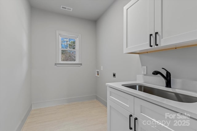 clothes washing area featuring electric dryer hookup, visible vents, washer hookup, a sink, and cabinet space