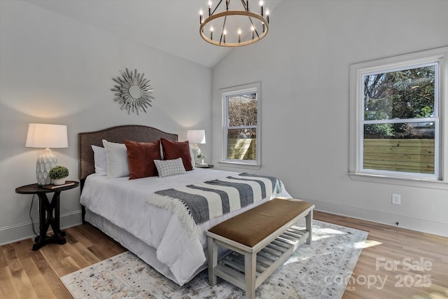bedroom with a chandelier, multiple windows, wood finished floors, and high vaulted ceiling
