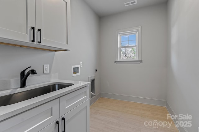 washroom with cabinet space, hookup for an electric dryer, washer hookup, light wood-type flooring, and baseboards