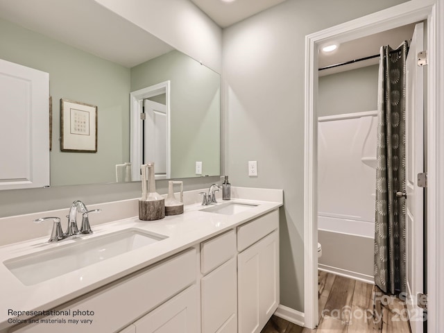 bathroom featuring double vanity, toilet, wood finished floors, and a sink