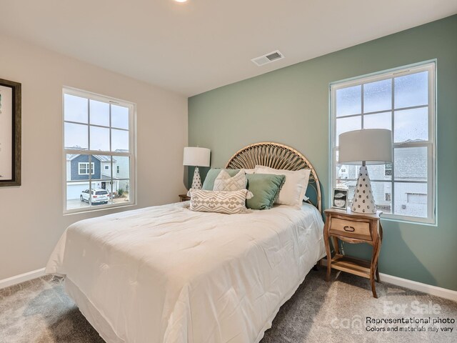 carpeted bedroom with visible vents, baseboards, and multiple windows