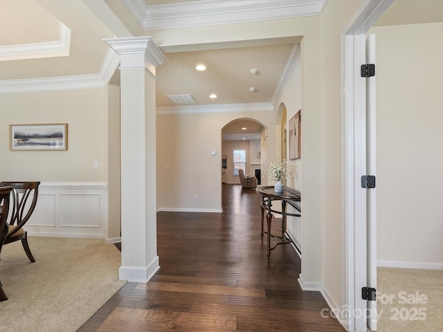 hall featuring dark wood-type flooring, ornamental molding, recessed lighting, arched walkways, and a decorative wall