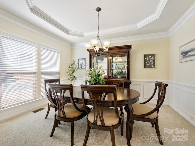 dining space featuring a chandelier, visible vents, light colored carpet, and a decorative wall