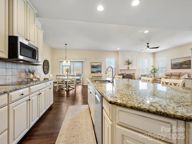 kitchen featuring dark wood-type flooring, a ceiling fan, a sink, tasteful backsplash, and appliances with stainless steel finishes