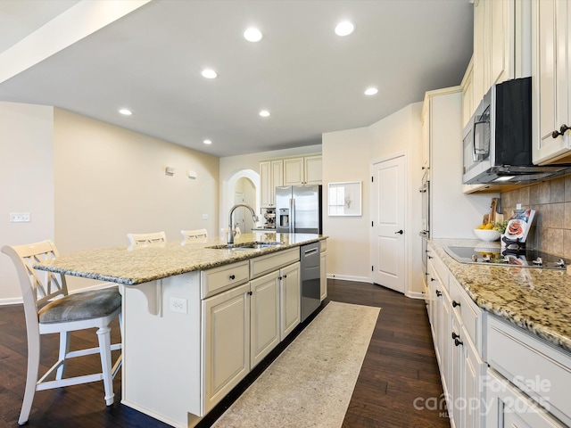 kitchen featuring a sink, a kitchen breakfast bar, backsplash, dark wood-style floors, and stainless steel appliances