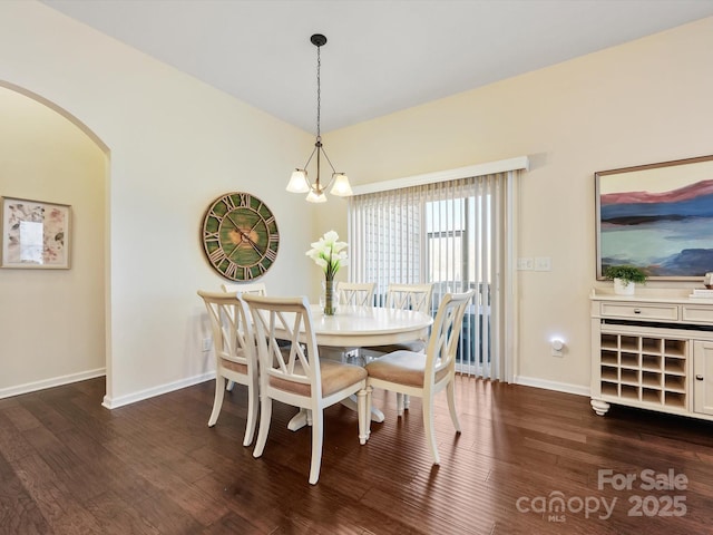 dining room with baseboards, arched walkways, and dark wood-style floors