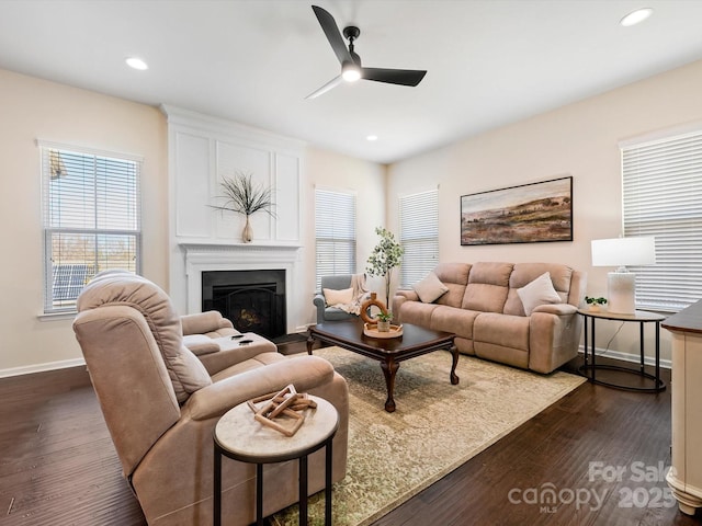 living room featuring dark wood finished floors, a fireplace, baseboards, and a ceiling fan