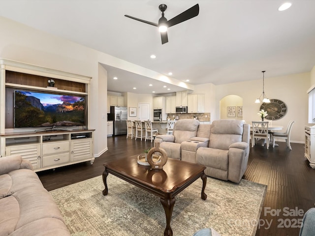 living area with baseboards, recessed lighting, arched walkways, ceiling fan, and dark wood-type flooring