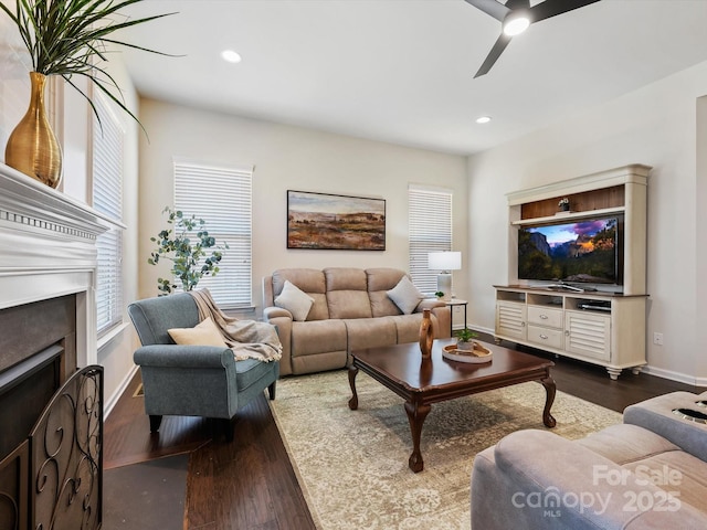 living area featuring baseboards, ceiling fan, recessed lighting, a fireplace, and dark wood-style floors