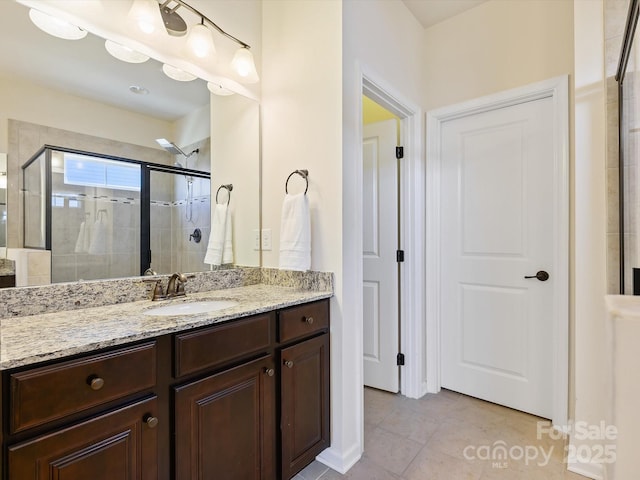 full bathroom featuring tile patterned floors, a stall shower, and vanity