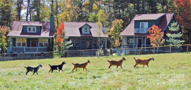 back of property featuring a rural view, fence, a yard, and a sunroom