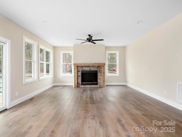 unfurnished living room with wood finished floors, a ceiling fan, visible vents, and baseboards