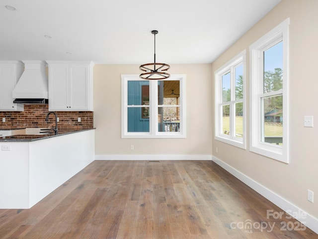 unfurnished dining area featuring wood finished floors, baseboards, and a sink