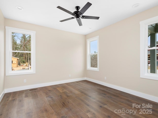 spare room featuring ceiling fan, visible vents, baseboards, and wood finished floors