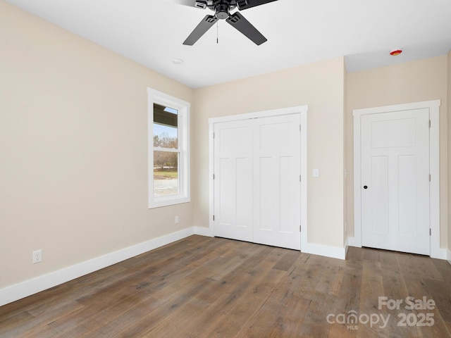 unfurnished bedroom with a closet, ceiling fan, baseboards, and wood finished floors