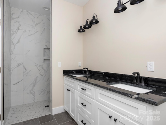 bathroom featuring double vanity, baseboards, a marble finish shower, and a sink