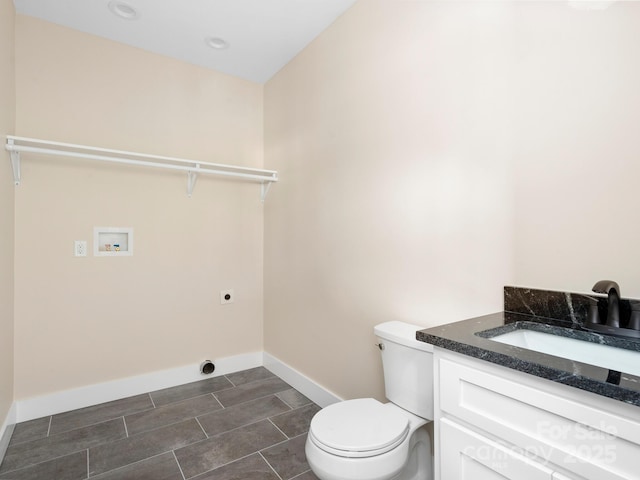 bathroom with toilet, vanity, and baseboards