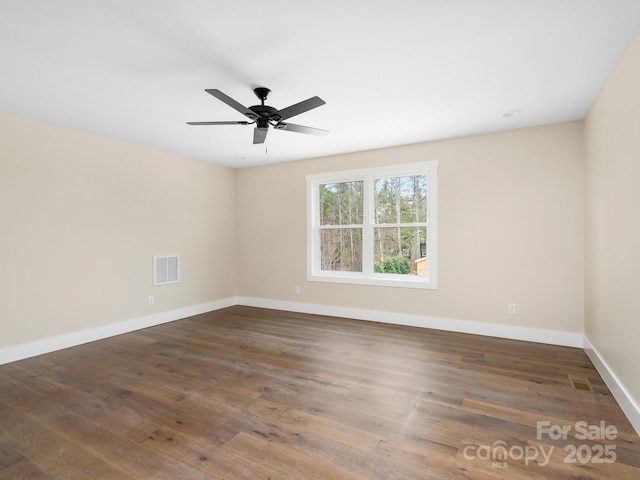 unfurnished room with a ceiling fan, wood finished floors, visible vents, and baseboards