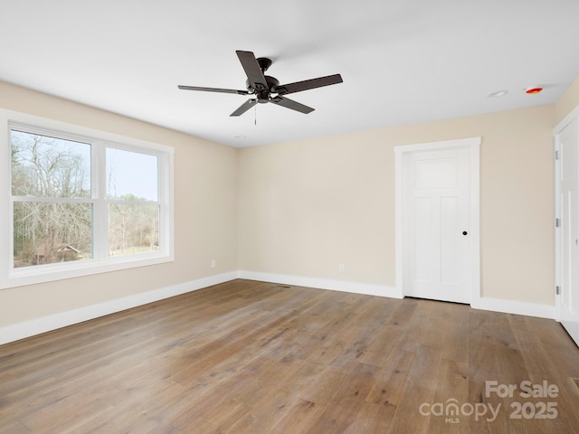 empty room featuring ceiling fan, baseboards, and wood finished floors