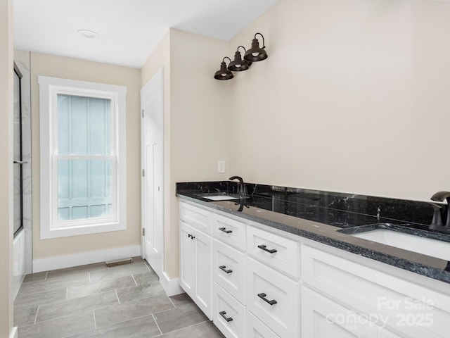 bathroom featuring a sink, an enclosed shower, baseboards, and double vanity