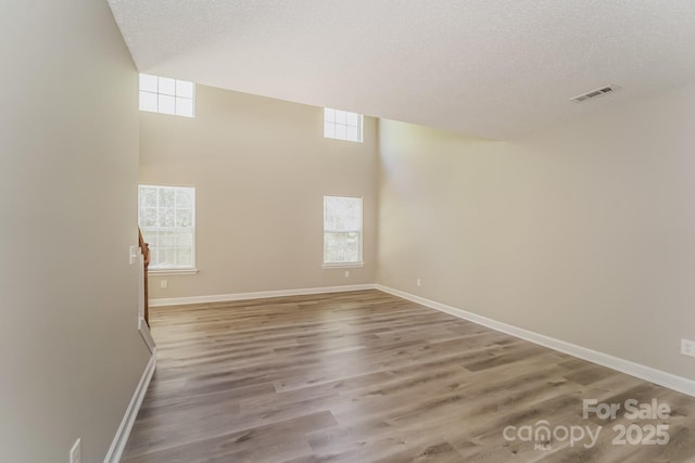 spare room with visible vents, a textured ceiling, and wood finished floors