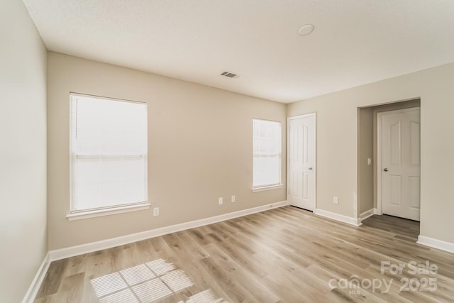 empty room featuring visible vents, baseboards, and light wood-style floors