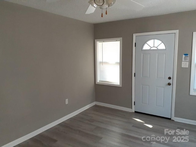 foyer entrance featuring a textured ceiling, a ceiling fan, baseboards, and wood finished floors