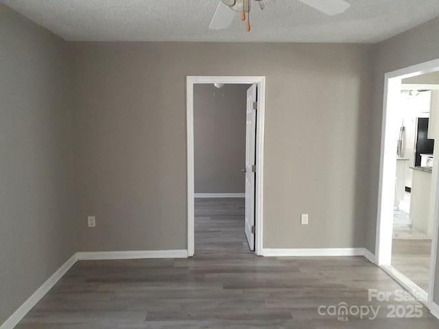 empty room featuring baseboards, a textured ceiling, and wood finished floors