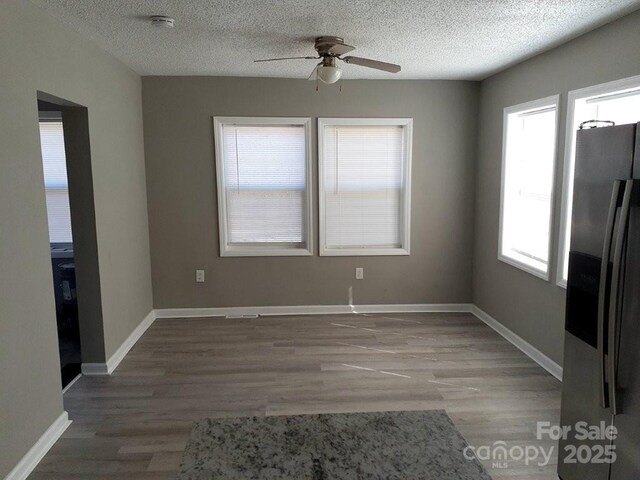 interior space with baseboards, a textured ceiling, and wood finished floors