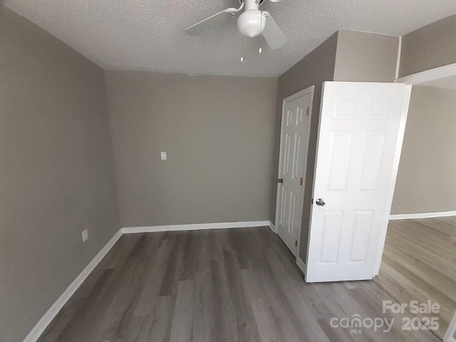 interior space featuring baseboards, a textured ceiling, and wood finished floors