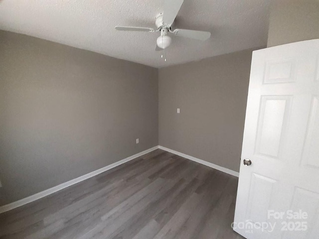 unfurnished room featuring baseboards, dark wood-type flooring, ceiling fan, and a textured ceiling