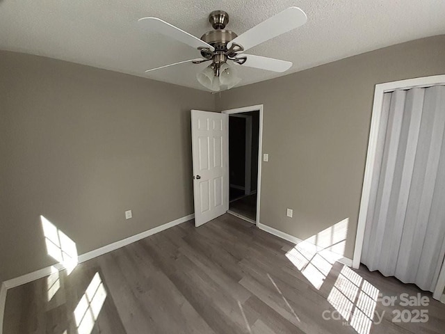 unfurnished room with a ceiling fan, wood finished floors, baseboards, and a textured ceiling