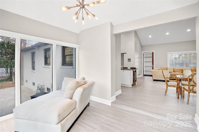 interior space with light wood-style floors, lofted ceiling, a notable chandelier, and baseboards
