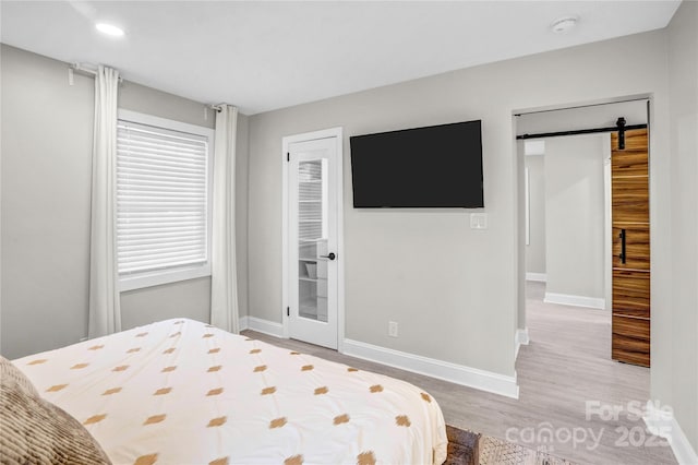 bedroom featuring recessed lighting, baseboards, a barn door, and wood finished floors