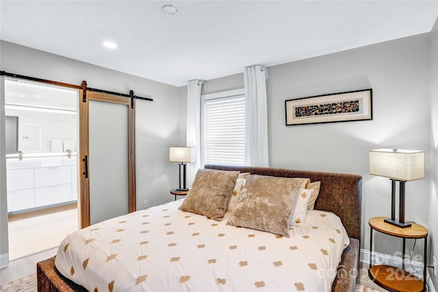 bedroom with recessed lighting, baseboards, a barn door, and wood finished floors
