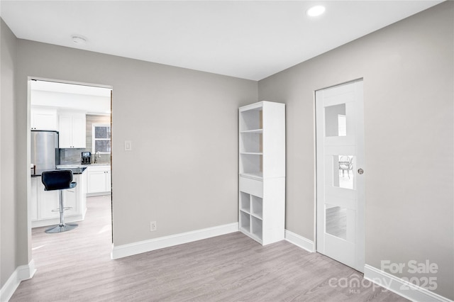 unfurnished bedroom with a sink, light wood-type flooring, baseboards, and recessed lighting