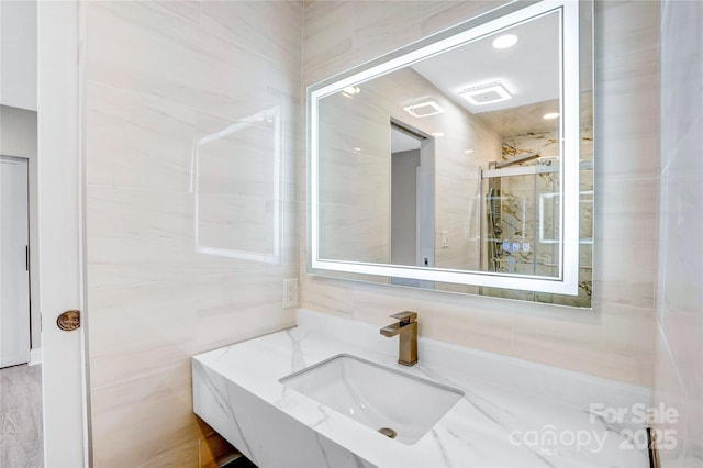 bathroom featuring vanity and tile walls