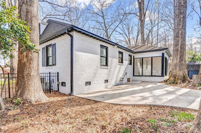 back of house featuring crawl space, a patio, brick siding, and fence