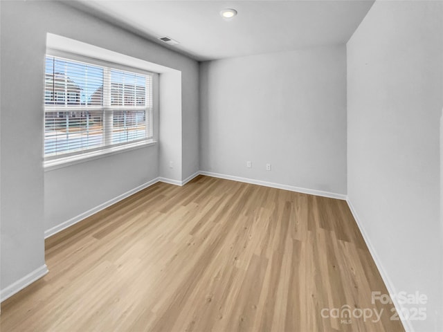 spare room with visible vents, baseboards, and wood finished floors