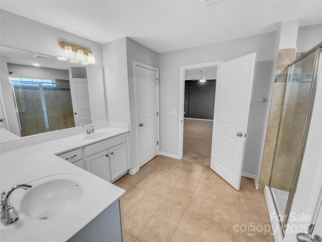 bathroom featuring a shower stall, double vanity, baseboards, and a sink