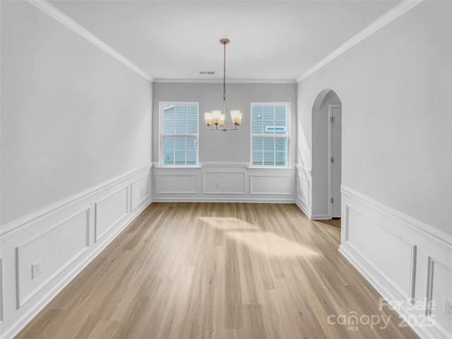 unfurnished dining area featuring visible vents, an inviting chandelier, light wood-style flooring, arched walkways, and crown molding