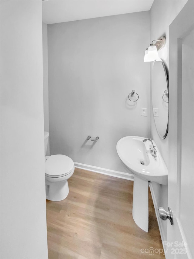 bathroom with toilet, wood finished floors, and baseboards